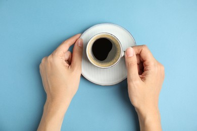 Woman with cup of hot aromatic espresso on light blue background, top view Photo of Woman with cup of hot aromatic espresso on light blue background, top view