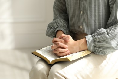 Religious woman praying over Bible indoors, closeup Photo of Religious woman praying over Bible indoors, closeup