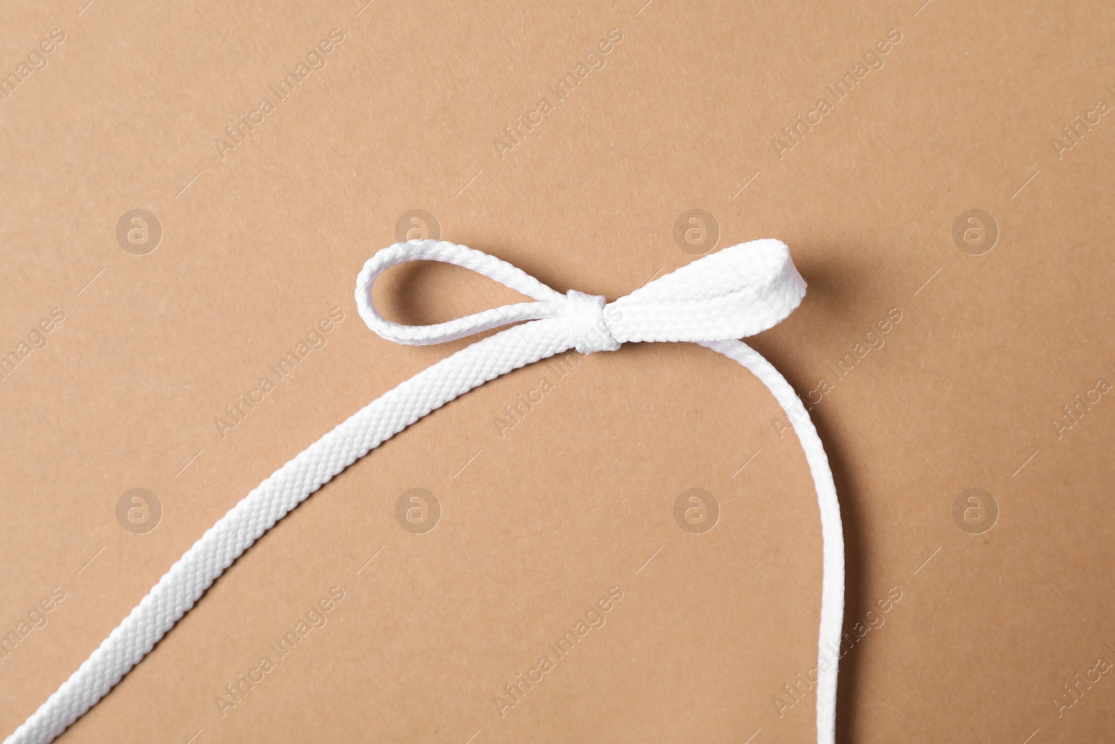 White shoelace on brown background, top view Photo of White shoelace on brown background, top view