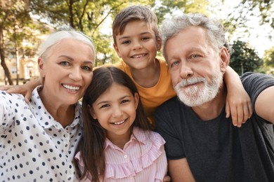 Happy grandparents with little children taking selfie in park Photo of Happy grandparents with little children taking selfie in park