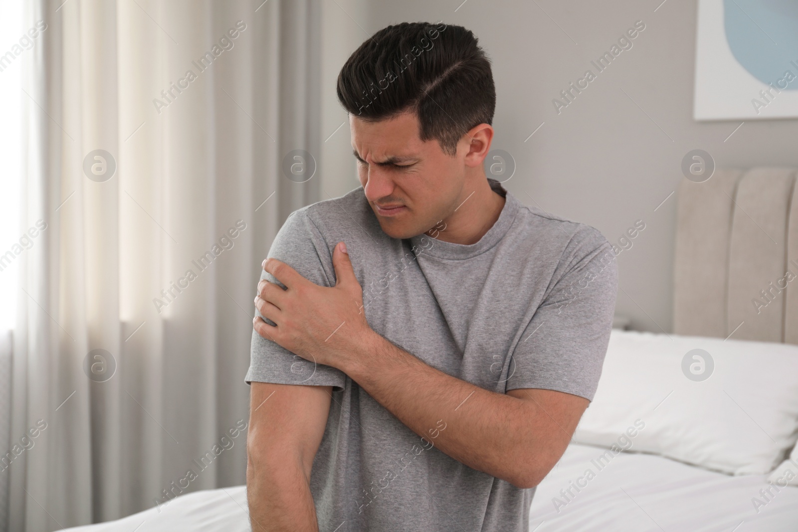 Man suffering from shoulder pain on bed at home Photo of Man suffering from shoulder pain on bed at home