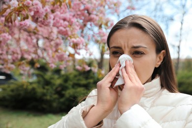 Woman suffering from seasonal pollen allergy near blossoming tree outdoors Photo of Woman suffering from seasonal pollen allergy near blossoming tree outdoors