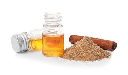 Bottles of cinnamon oil, powder and stick on white background Photo of Bottles of cinnamon oil, powder and stick on white background