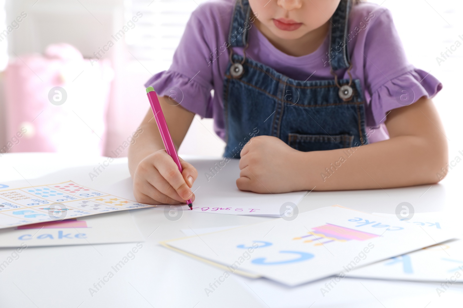 Little girl writing numbers in classroom at English lesson, closeup Photo of Little girl writing numbers in classroom at English lesson, closeup