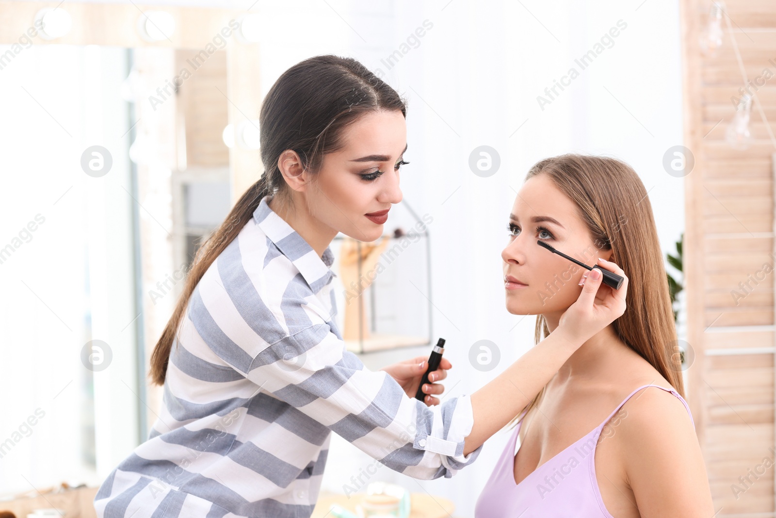 Professional visage artist applying makeup on woman's face in salon Photo of Professional visage artist applying makeup on woman's face in salon