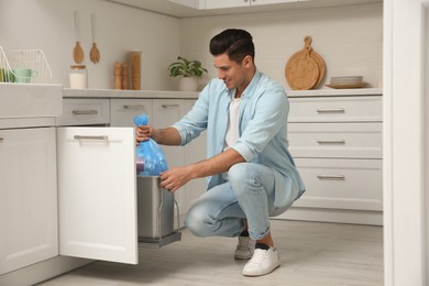 Man taking garbage bag out of bin at home Photo of Man taking garbage bag out of bin at home