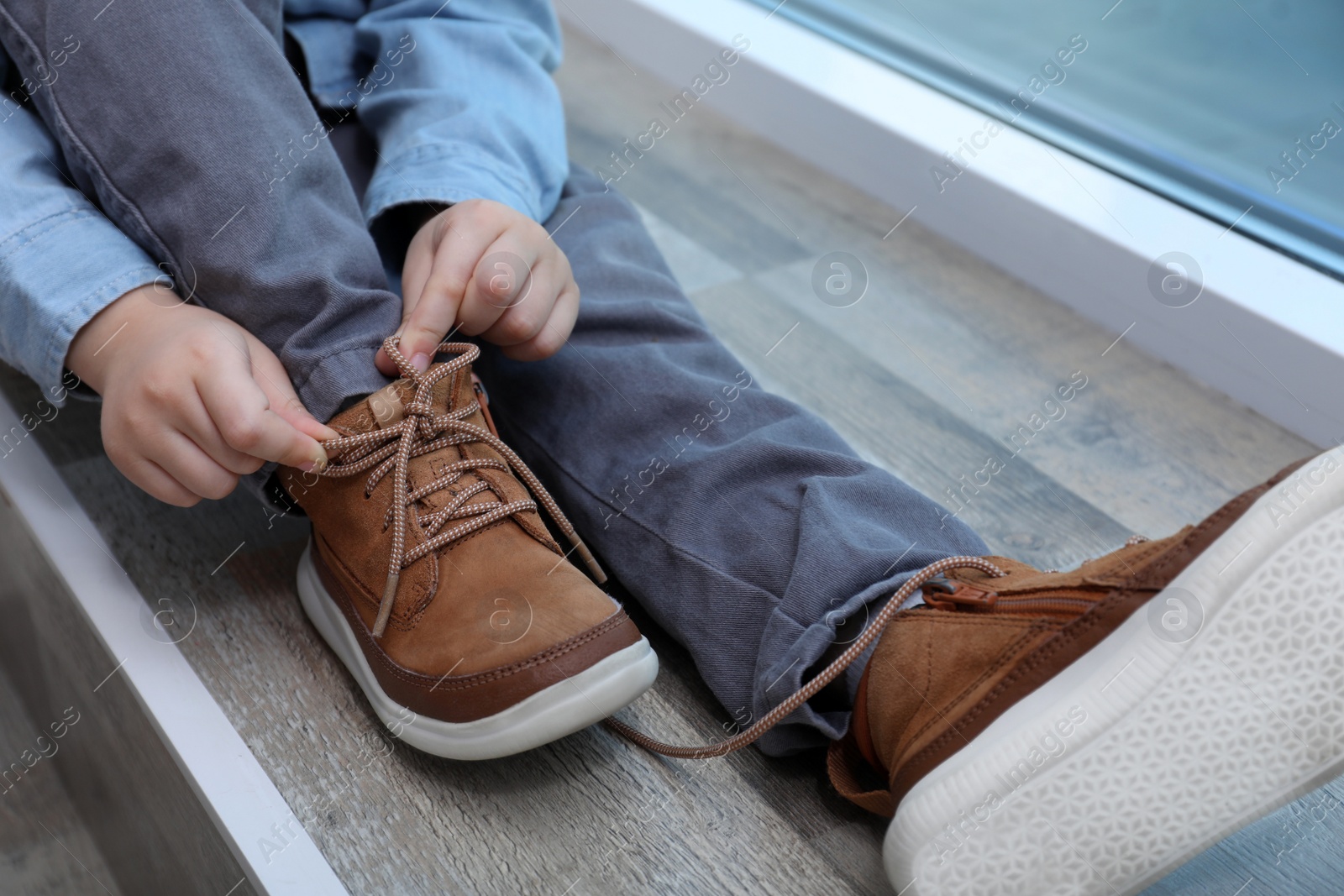 Little boy tying shoe laces at home, closeup Photo of Little boy tying shoe laces at home, closeup