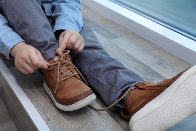 Little boy tying shoe laces at home, closeup Photo of Little boy tying shoe laces at home, closeup