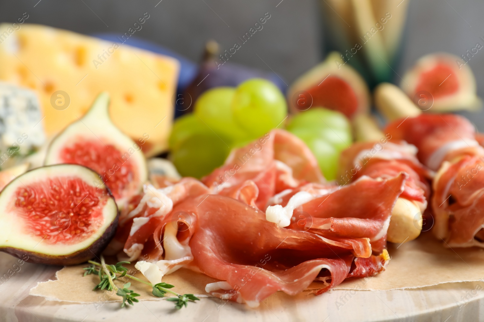 Board with delicious figs, cheese, grapes and bread with proscuitto, closeup Photo of Board with delicious figs, cheese, grapes and bread with proscuitto, closeup