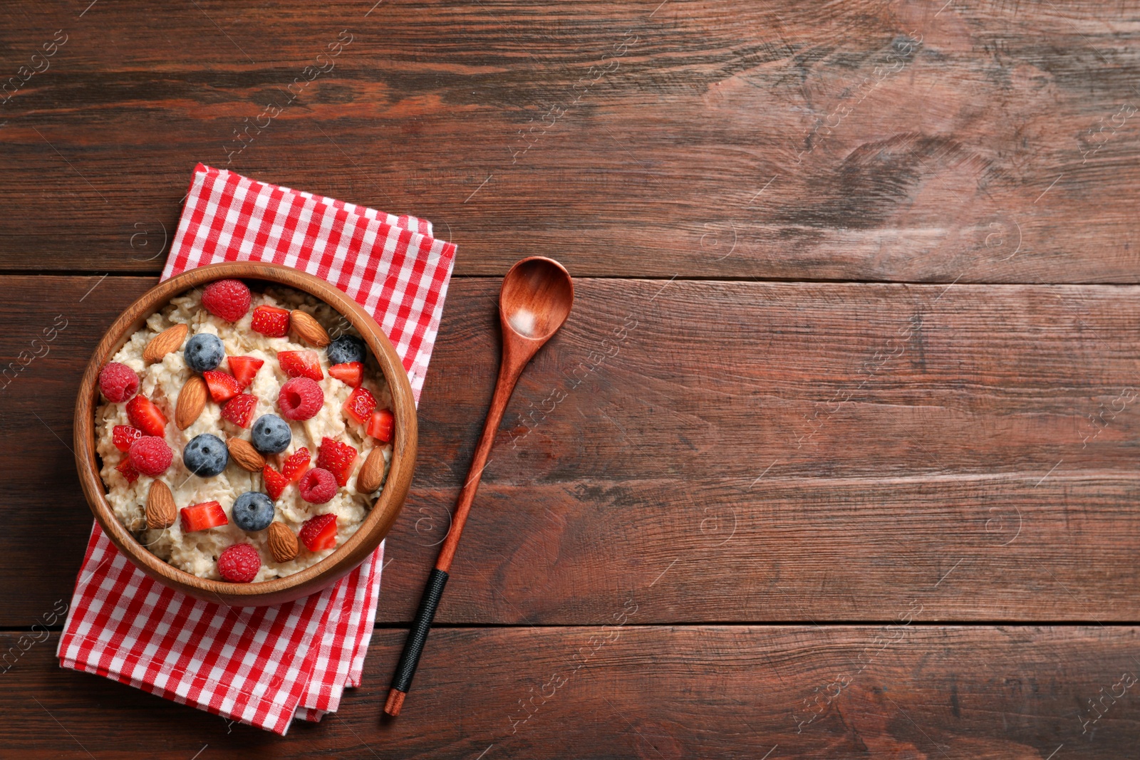 Tasty oatmeal porridge with berries and almond nuts served on wooden table, flat lay. Space for text Photo of Tasty oatmeal porridge with berries and almond nuts served on wooden table, flat lay. Space for text