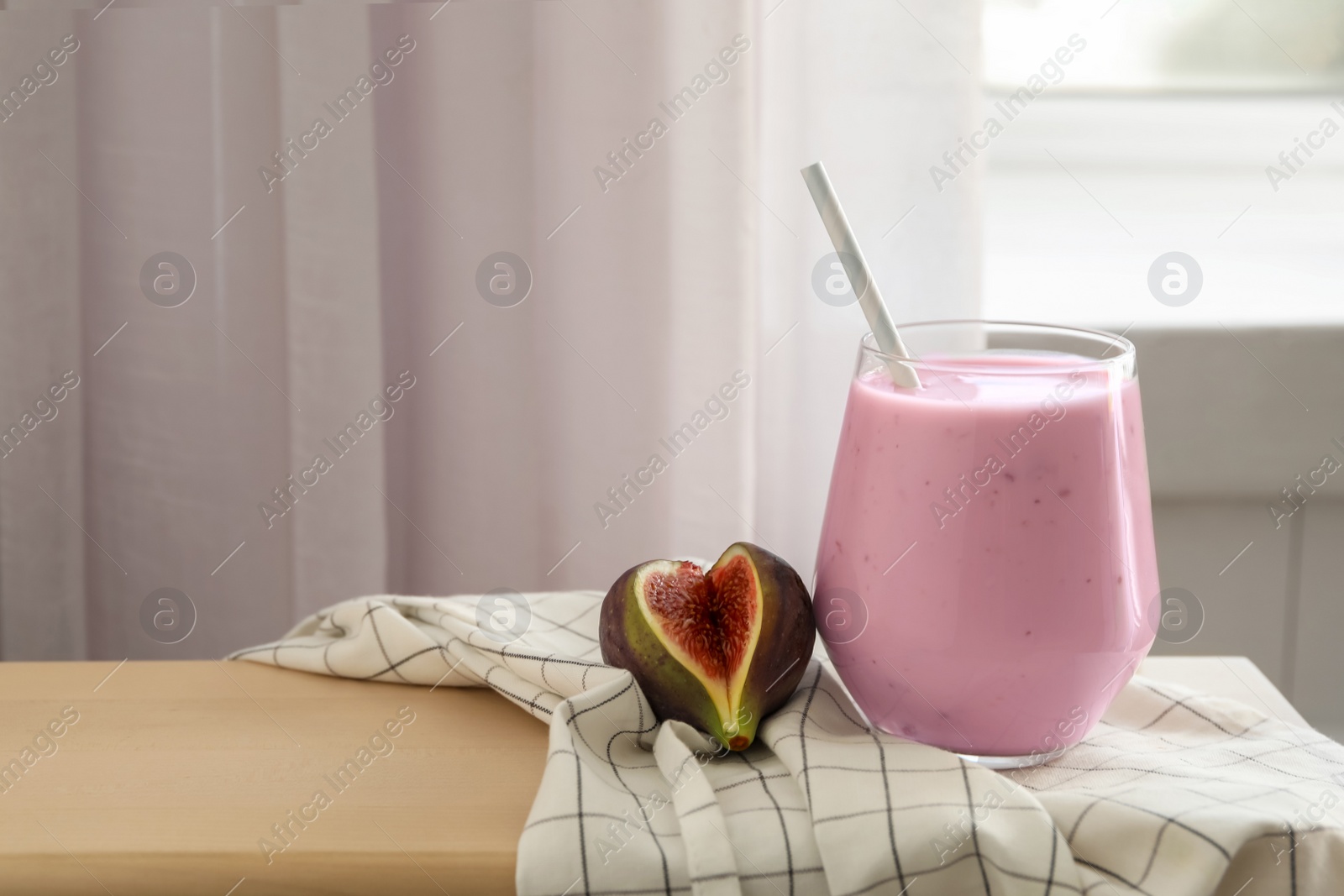Delicious fig smoothie in glass on table indoors Photo of Delicious fig smoothie in glass on table indoors