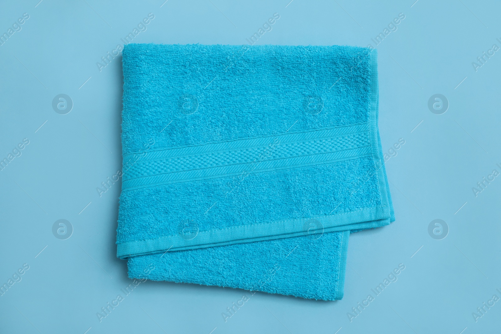 Folded soft beach towel on light blue background, top view Photo of Folded soft beach towel on light blue background, top view