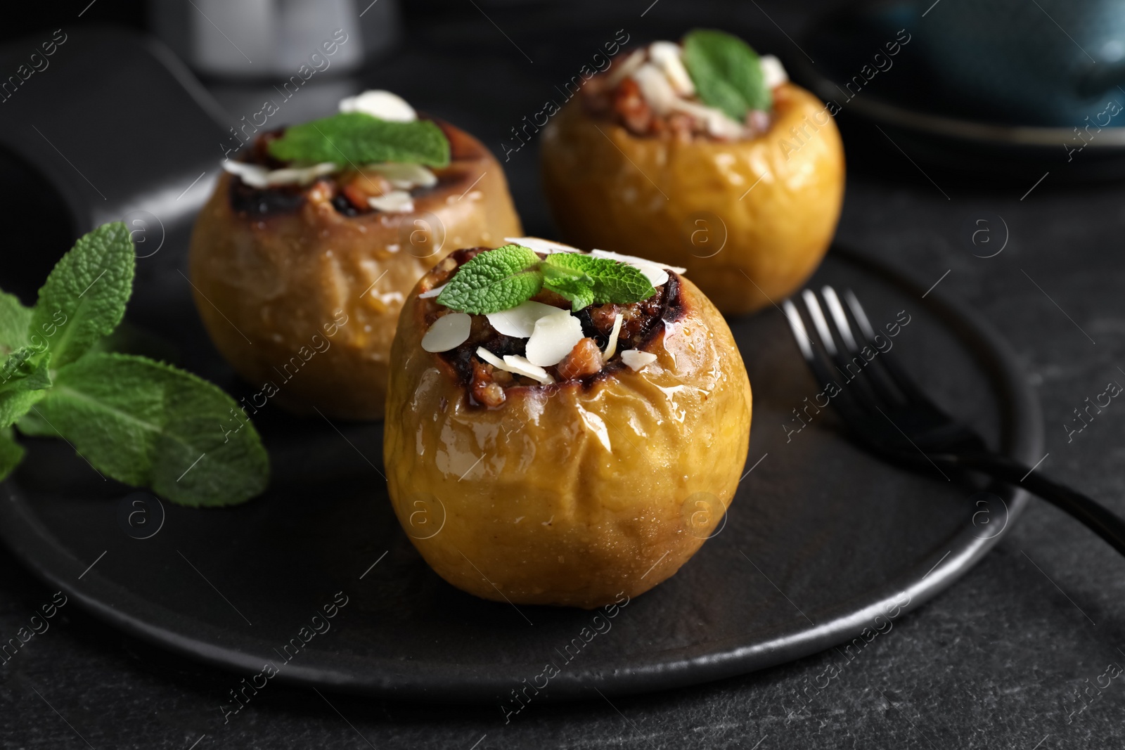 Delicious baked apples with nuts and mint served on black table Photo of Delicious baked apples with nuts and mint served on black table