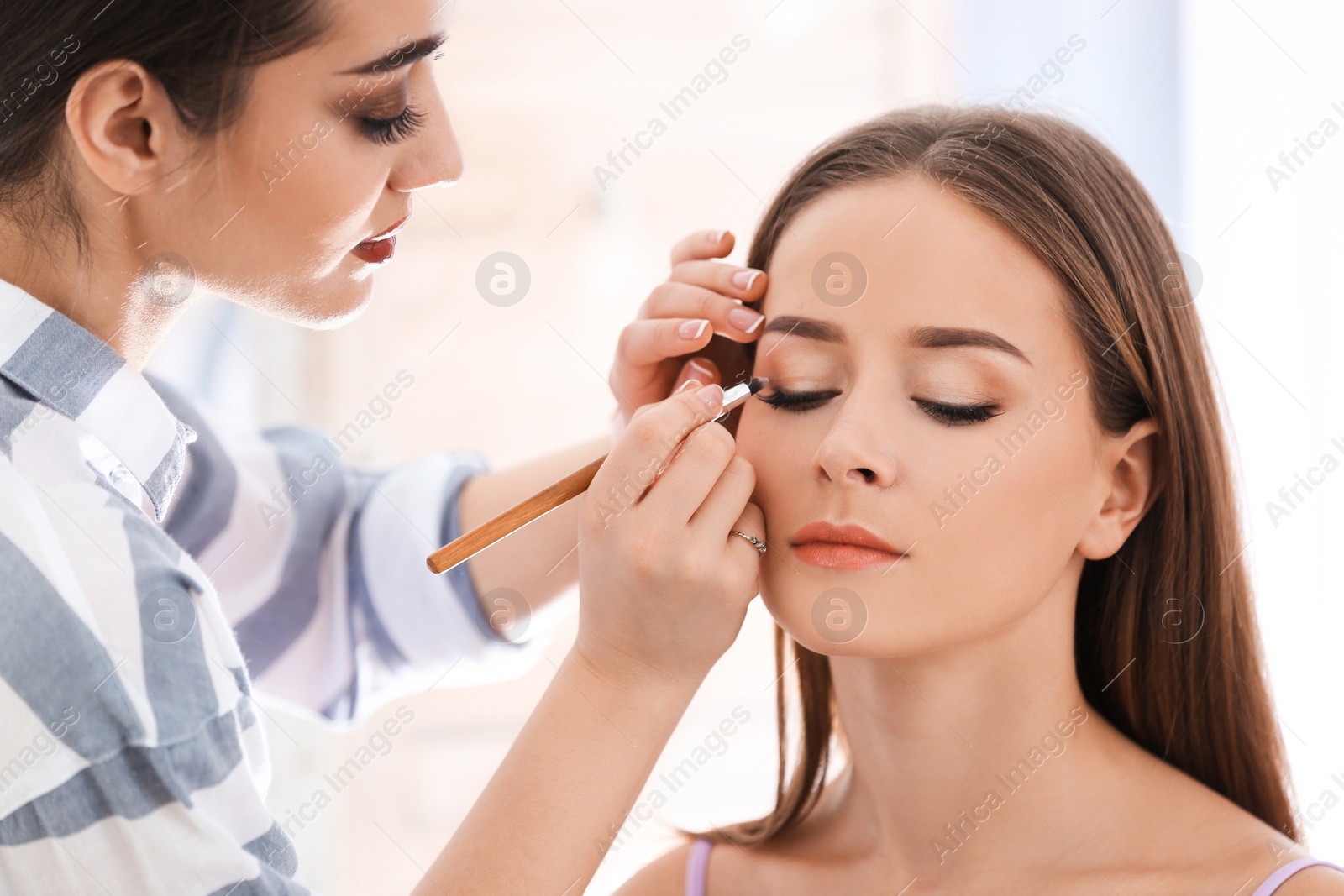 Professional visage artist applying makeup on woman's face in salon Photo of Professional visage artist applying makeup on woman's face in salon
