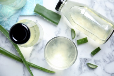 Fresh aloe drink and leaves on white marble table, flat lay Photo of Fresh aloe drink and leaves on white marble table, flat lay