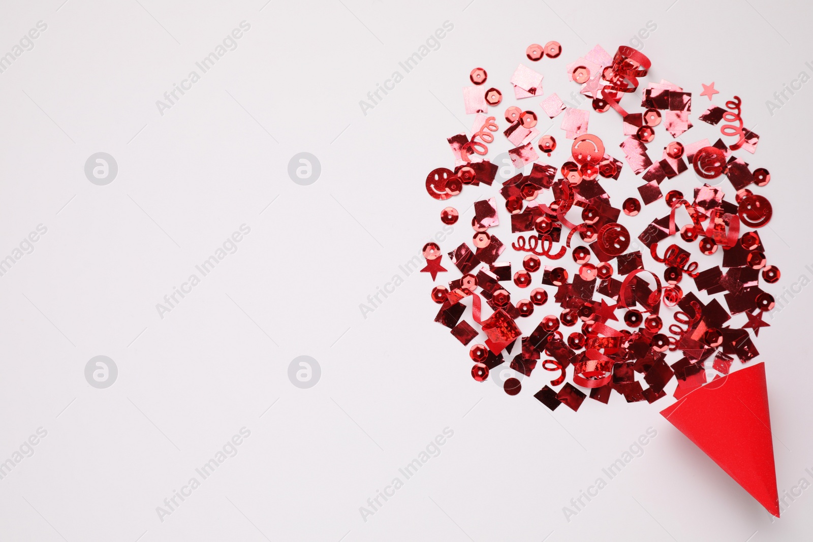 Shiny red confetti bursting out of party cracker on light background, top view. Space for text Photo of Shiny red confetti bursting out of party cracker on light background, top view. Space for text