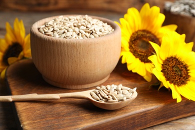 Raw peeled sunflower seeds and flowers on wooden board Photo of Raw peeled sunflower seeds and flowers on wooden board