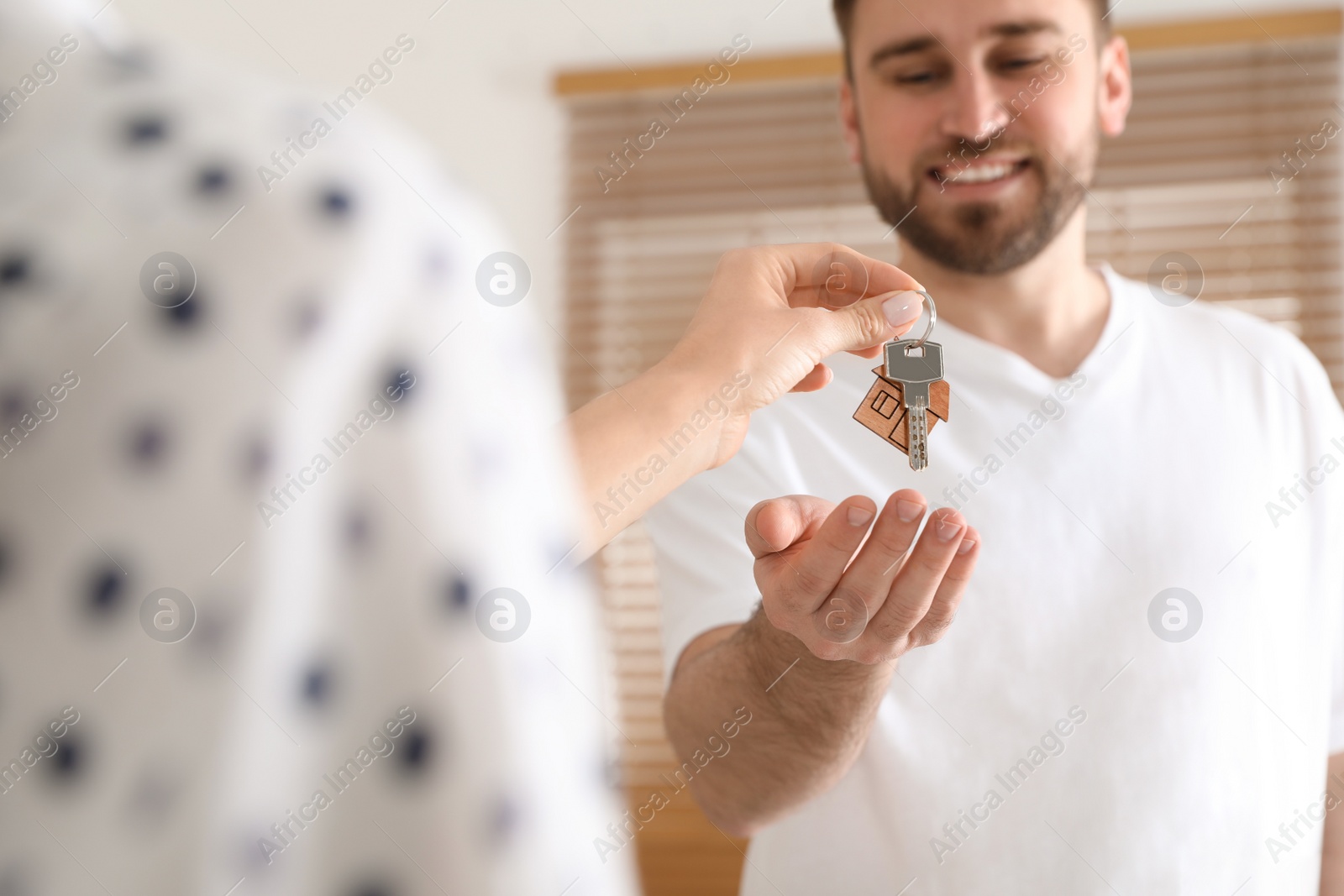 Real estate agent giving key to happy young man in new house, closeup Photo of Real estate agent giving key to happy young man in new house, closeup