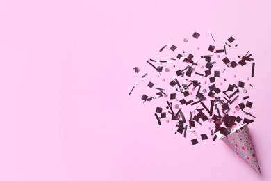 Shiny silver confetti bursting out of party cracker on pink background, top view. Space for text Photo of Shiny silver confetti bursting out of party cracker on pink background, top view. Space for text