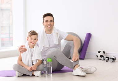 Dad and his son with bottles of water in gym Photo of Dad and his son with bottles of water in gym