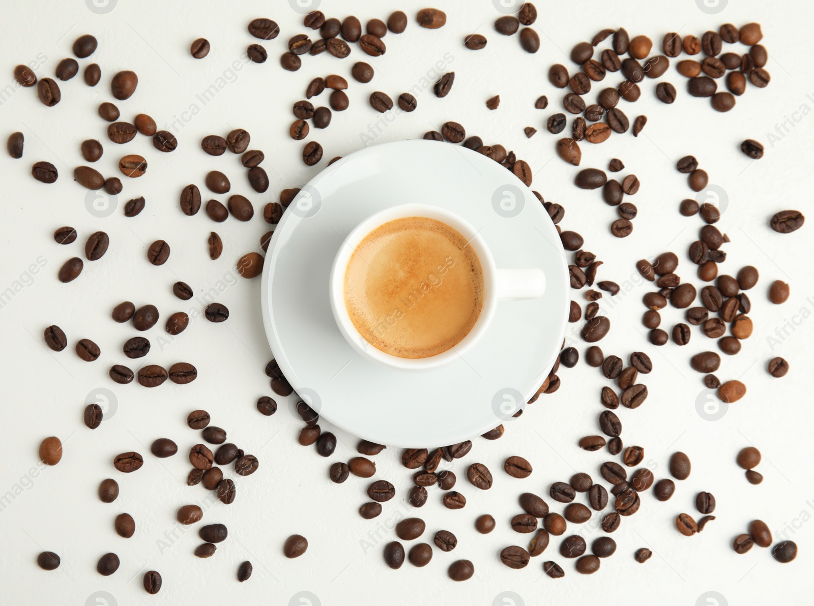 Cup of hot aromatic espresso and roasted beans on white table, flat lay Photo of Cup of hot aromatic espresso and roasted beans on white table, flat lay