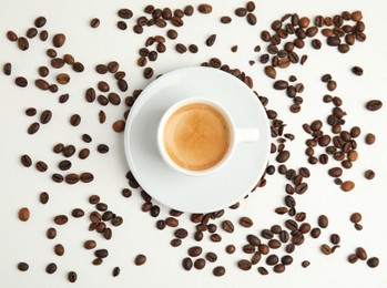 Cup of hot aromatic espresso and roasted beans on white table, flat lay Photo of Cup of hot aromatic espresso and roasted beans on white table, flat lay