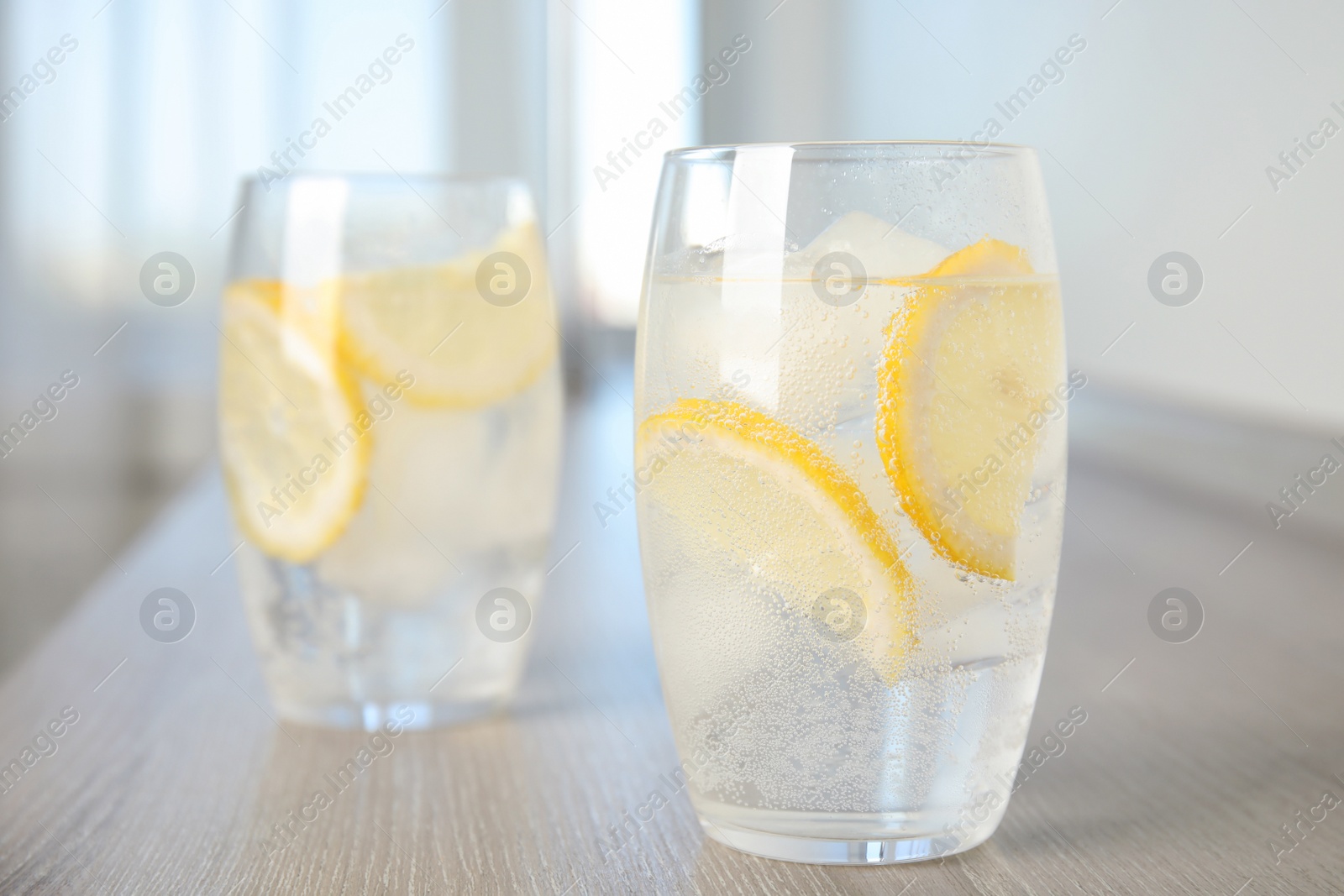 Soda water with lemon slices and ice cubes on wooden table indoors. Space for text Photo of Soda water with lemon slices and ice cubes on wooden table indoors. Space for text