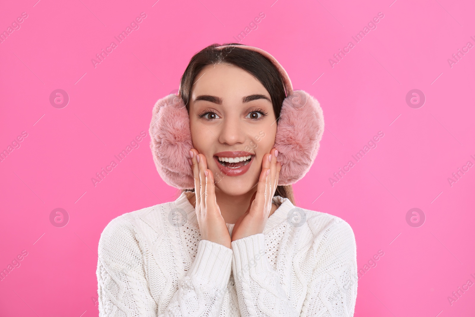 Beautiful young woman wearing earmuffs on pink background Photo of Beautiful young woman wearing earmuffs on pink background
