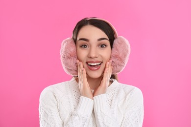 Beautiful young woman wearing earmuffs on pink background Photo of Beautiful young woman wearing earmuffs on pink background