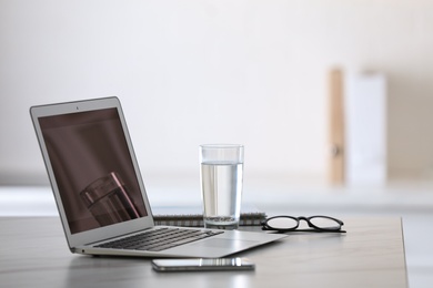 Modern workplace with laptop on grey table in office Photo of Modern workplace with laptop on grey table in office