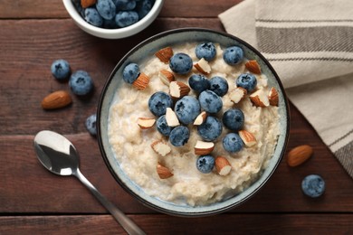 Tasty oatmeal porridge with blueberries and almond nuts served on wooden table, flat lay Photo of Tasty oatmeal porridge with blueberries and almond nuts served on wooden table, flat lay