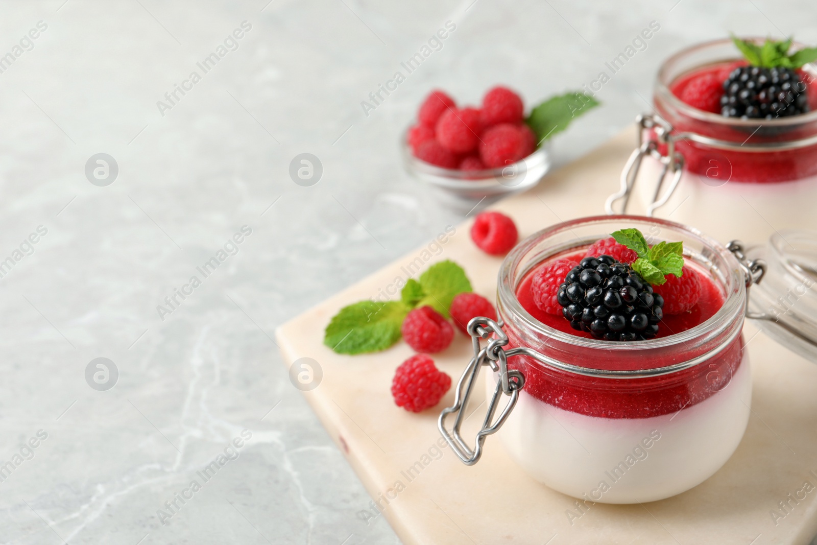 Delicious panna cotta with fruit coulis and fresh berries on light grey table. Space for text Photo of Delicious panna cotta with fruit coulis and fresh berries on light grey table. Space for text