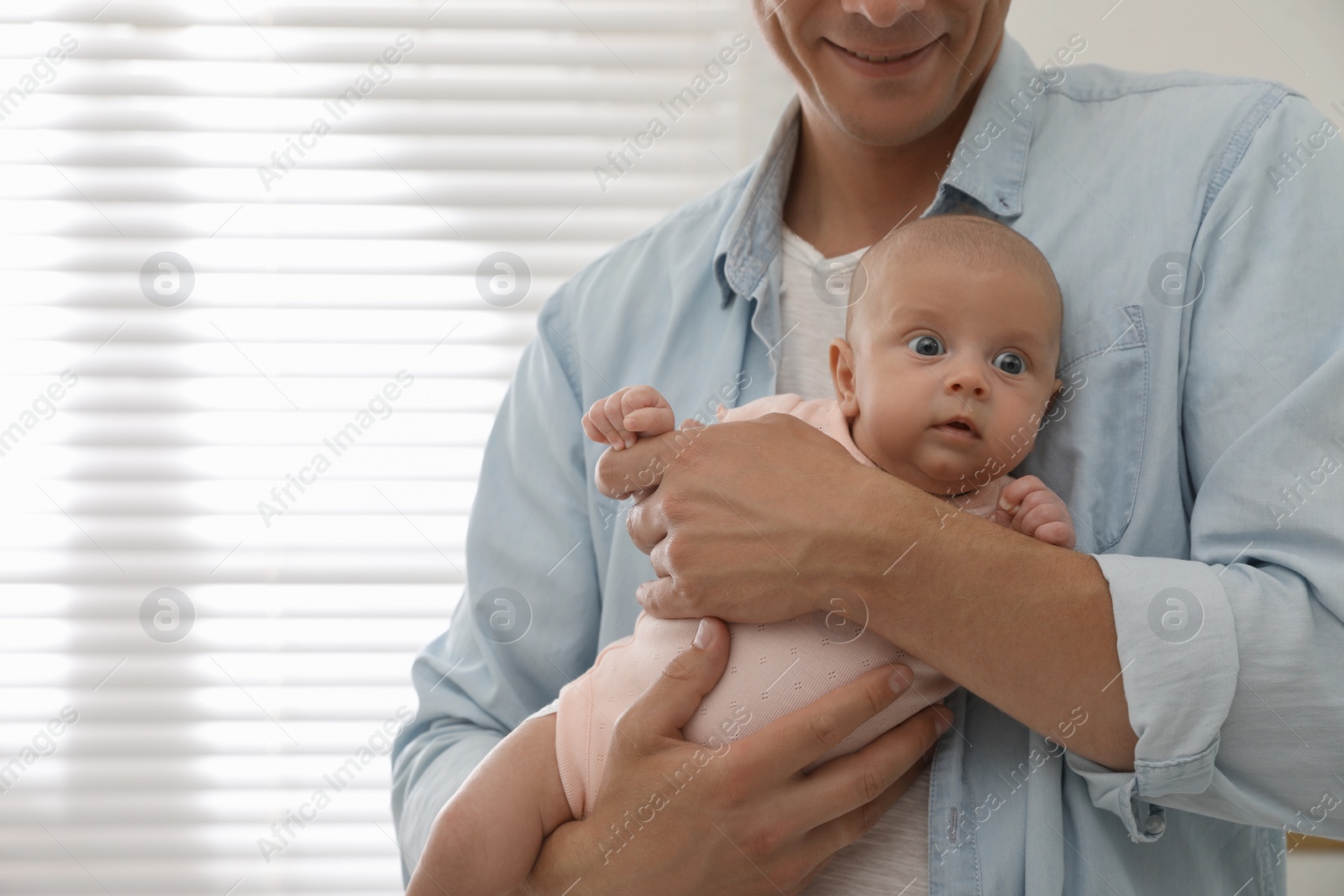 Happy father holding his cute little baby at home, closeup. Space for text Photo of Happy father holding his cute little baby at home, closeup. Space for text