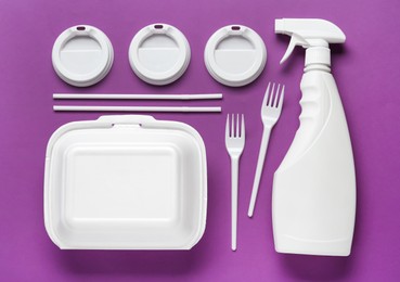 Plastic dishware and sprayer on purple background, flat lay Photo of Plastic dishware and sprayer on purple background, flat lay
