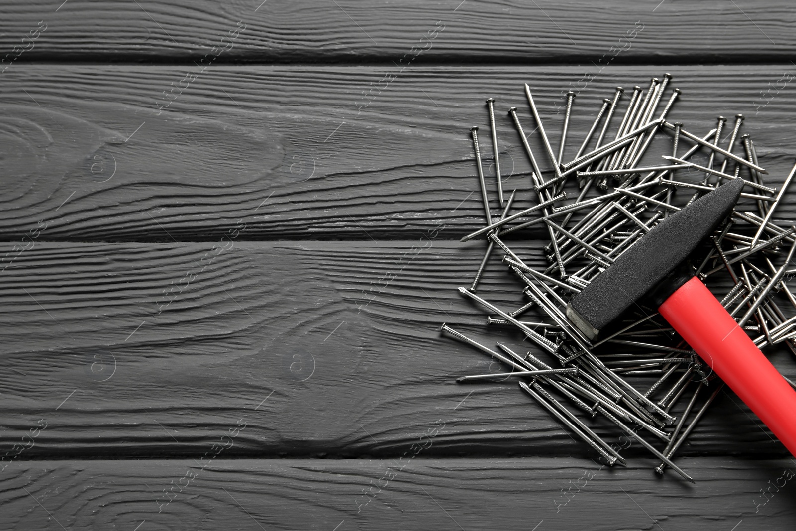 Hammer and metal nails on black wooden table, flat lay. Space for text Photo of Hammer and metal nails on black wooden table, flat lay. Space for text