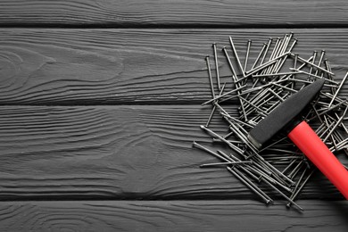 Hammer and metal nails on black wooden table, flat lay. Space for text Photo of Hammer and metal nails on black wooden table, flat lay. Space for text