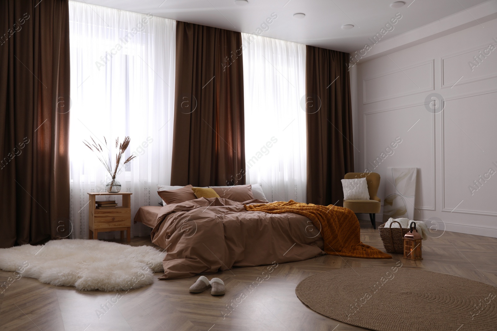 Bed with brown linens in stylish room interior Photo of Bed with brown linens in stylish room interior
