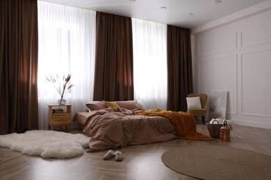 Bed with brown linens in stylish room interior Photo of Bed with brown linens in stylish room interior