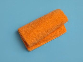 Rolled orange beach towel on light blue background, top view Photo of Rolled orange beach towel on light blue background, top view