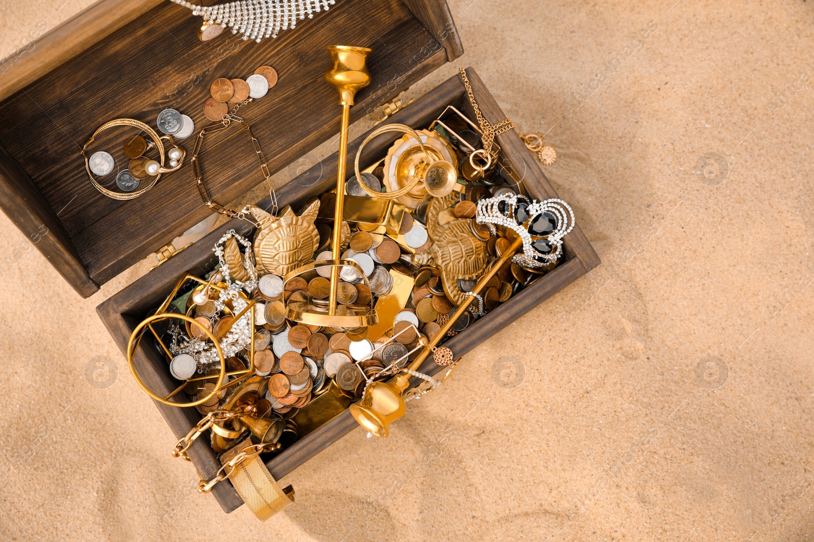 Open wooden treasure chest on sand, above view. Space for text Photo of Open wooden treasure chest on sand, above view. Space for text