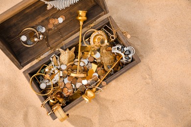Open wooden treasure chest on sand, above view. Space for text Photo of Open wooden treasure chest on sand, above view. Space for text