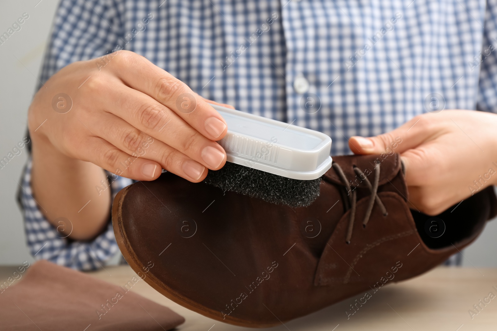 Woman taking care of stylish shoe at wooden table, closeup Photo of Woman taking care of stylish shoe at wooden table, closeup