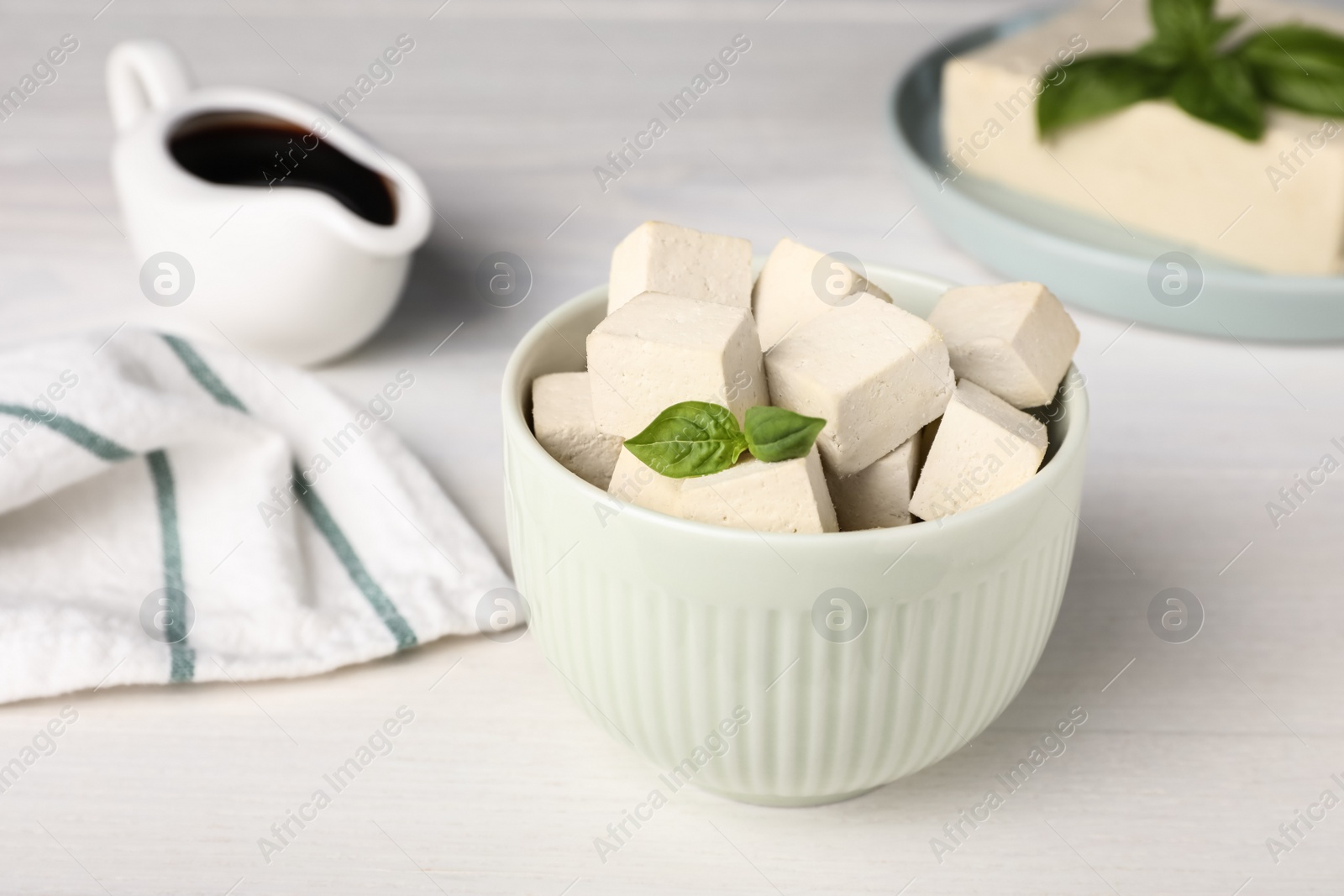 Delicious tofu with basil on white wooden table Photo of Delicious tofu with basil on white wooden table