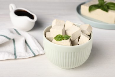 Delicious tofu with basil on white wooden table Photo of Delicious tofu with basil on white wooden table