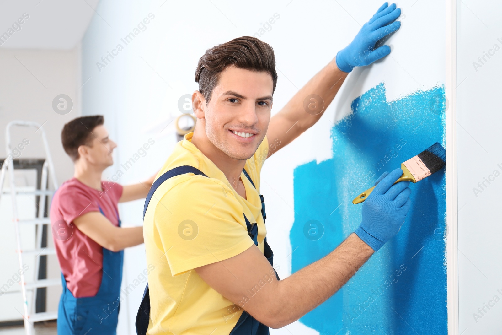 Male decorator painting wall with brush indoors Photo of Male decorator painting wall with brush indoors