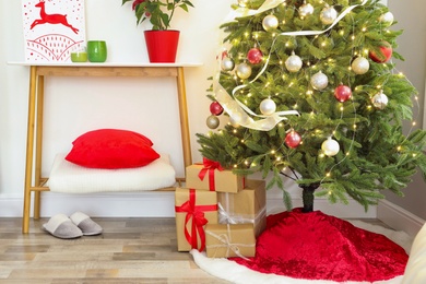 Beautiful Christmas tree with red skirt indoors Photo of Beautiful Christmas tree with red skirt indoors