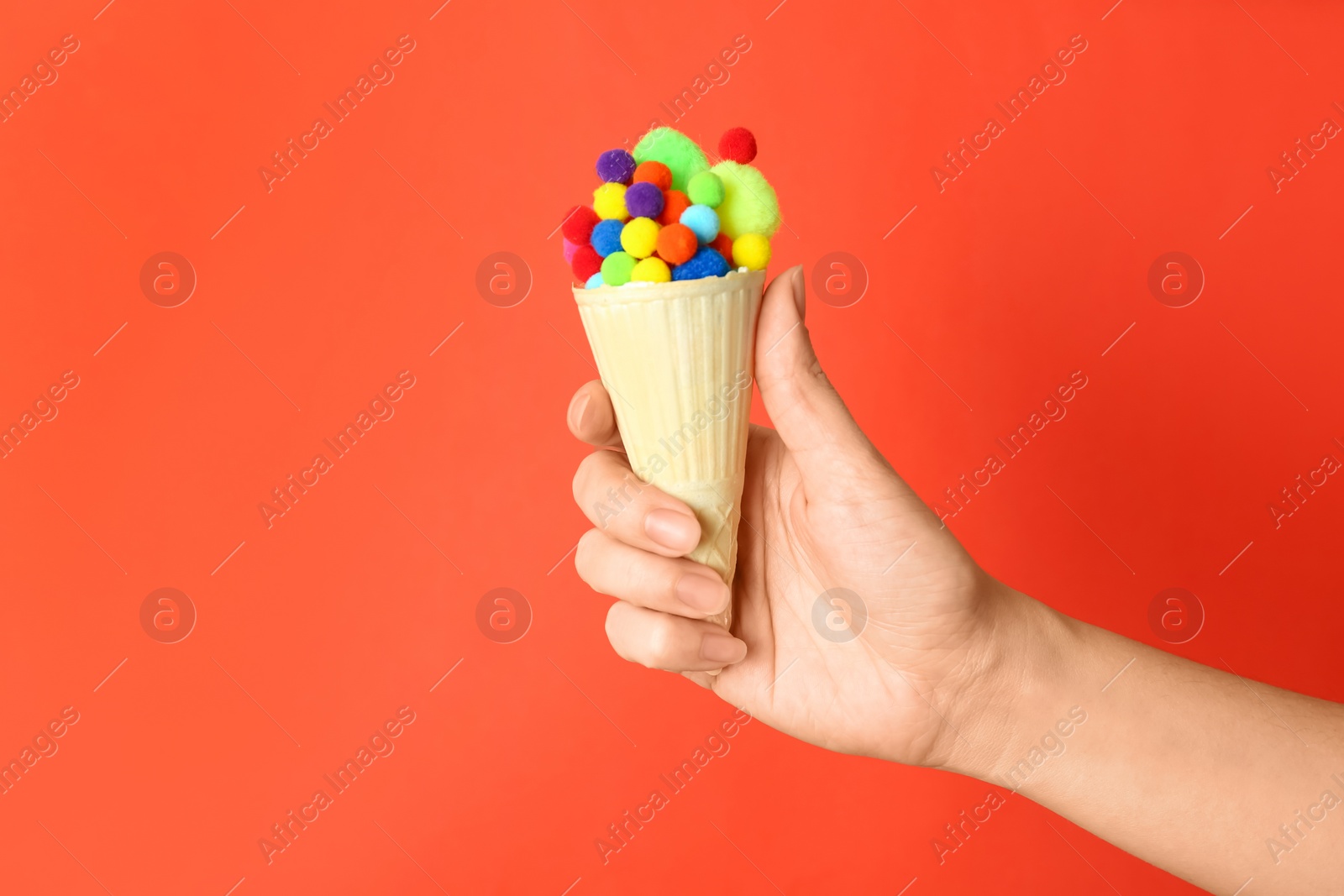 Woman holding ice cream waffle with fluffy balls on coral background, closeup Photo of Woman holding ice cream waffle with fluffy balls on coral background, closeup