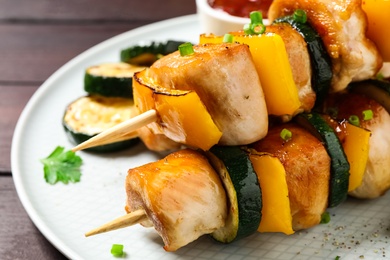 Delicious chicken shish kebabs with vegetables on wooden table, closeup Photo of Delicious chicken shish kebabs with vegetables on wooden table, closeup