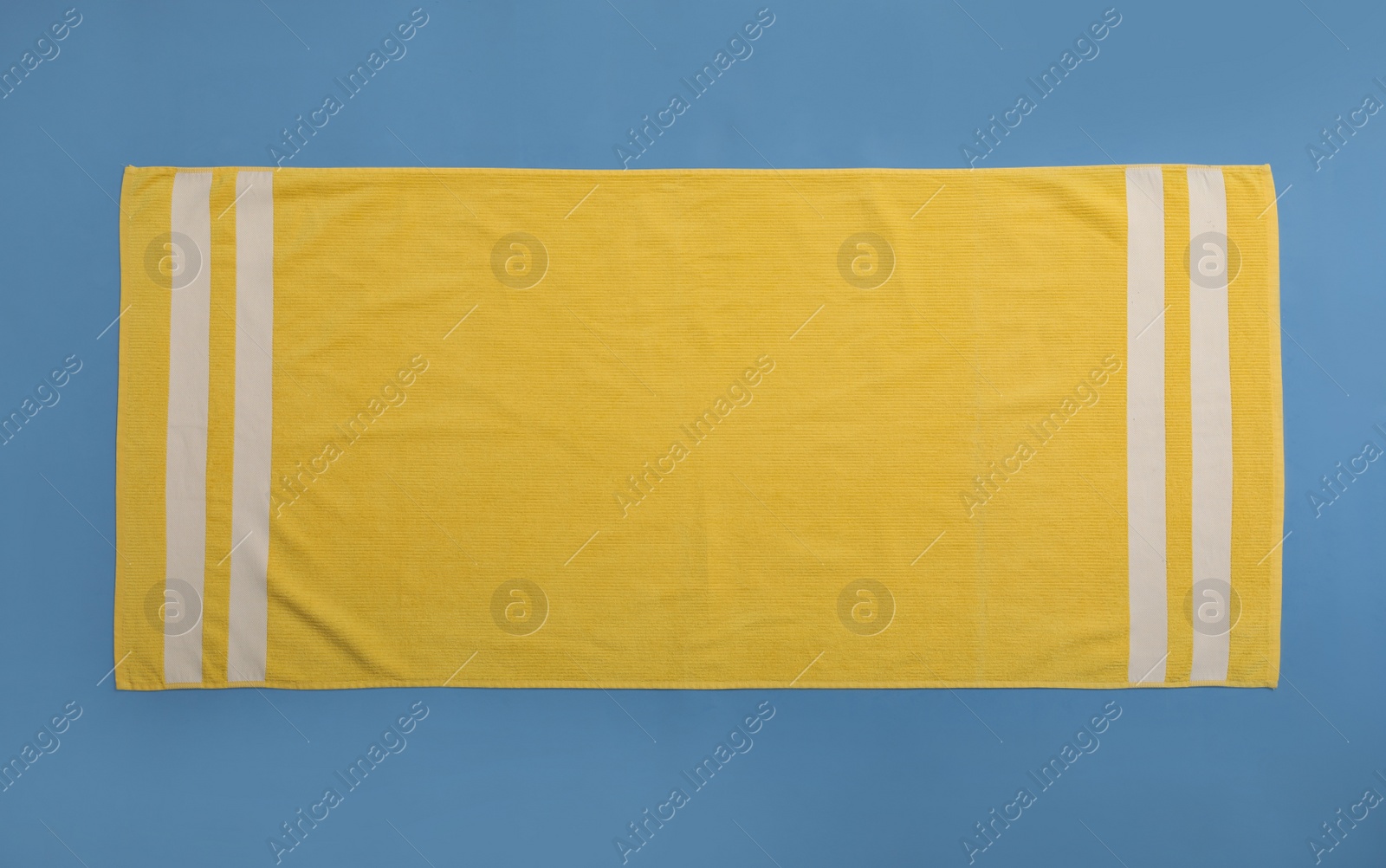 Photo of Yellow beach towel on blue background, top view
