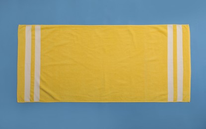 Yellow beach towel on blue background, top view Photo of Yellow beach towel on blue background, top view